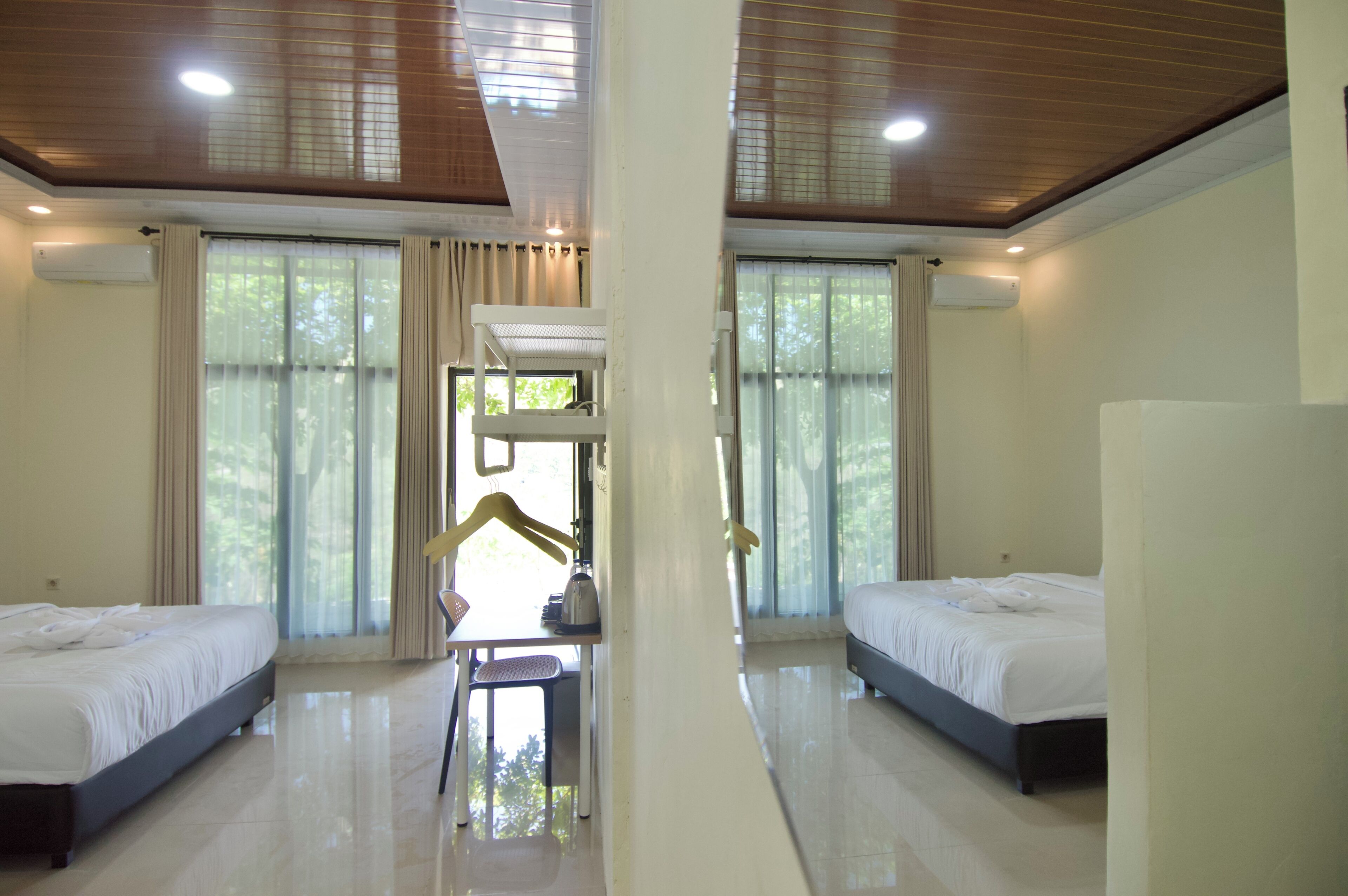 Habitación de hotel con dos camas, una mesa y una silla.