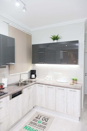 A modern kitchen with a dishwasher, double sink, and a coffee maker. - Piraiki Seaside Apartment (Pireas)