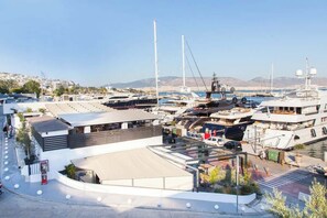 A marina with multiple yachts docked, a covered area with seating, and a view of the surrounding landscape. - Piraiki Seaside Apartment (Pireas)