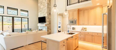 A modern kitchen with wooden cabinets, a stainless steel refrigerator, and a built-in oven.