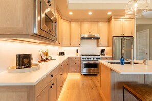 A modern kitchen with wooden cabinets, stainless steel appliances, and a central island. - Relax. Recharge. Repeat in DVE, Hot Tub, Pet Friendly (Heber City)
