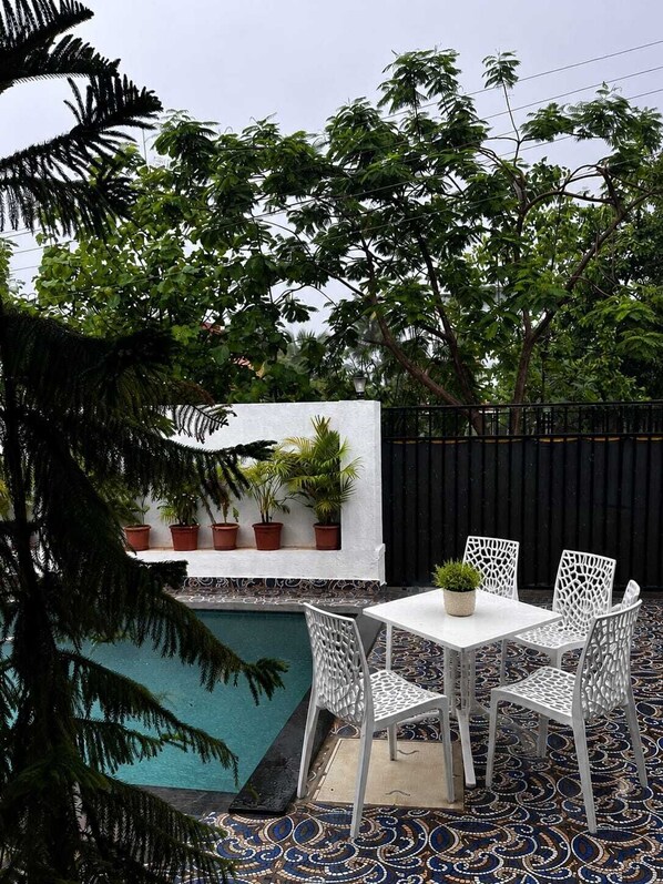 Une terrasse extérieure avec une piscine, des chaises blanches et des plantes en pot.