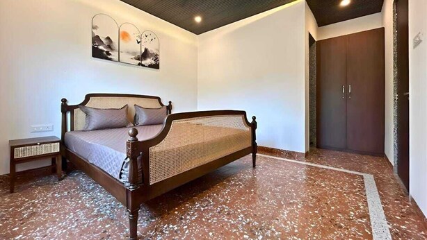 A bedroom with a bed, a nightstand, a wardrobe, and a ceiling fan. - Coastal Palm (Alibag)