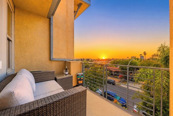 A balcony with wicker furniture, a bottle of wine, and a decorative mask. - Heart Of North Park, Mins To Beach & Restaurants (San Diego)