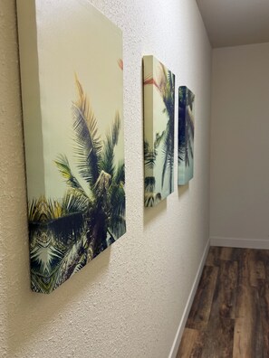 Ein Flur mit drei an der Wand befestigten Kunstwerken, die Palmen zeigen.