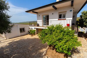 A two-story house with a balcony, stone flooring, and a view of the landscape.