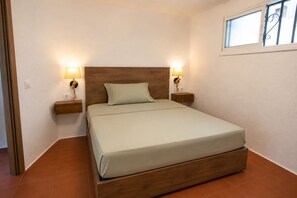 A single bed with a wooden headboard, two bedside lamps, and a window above.