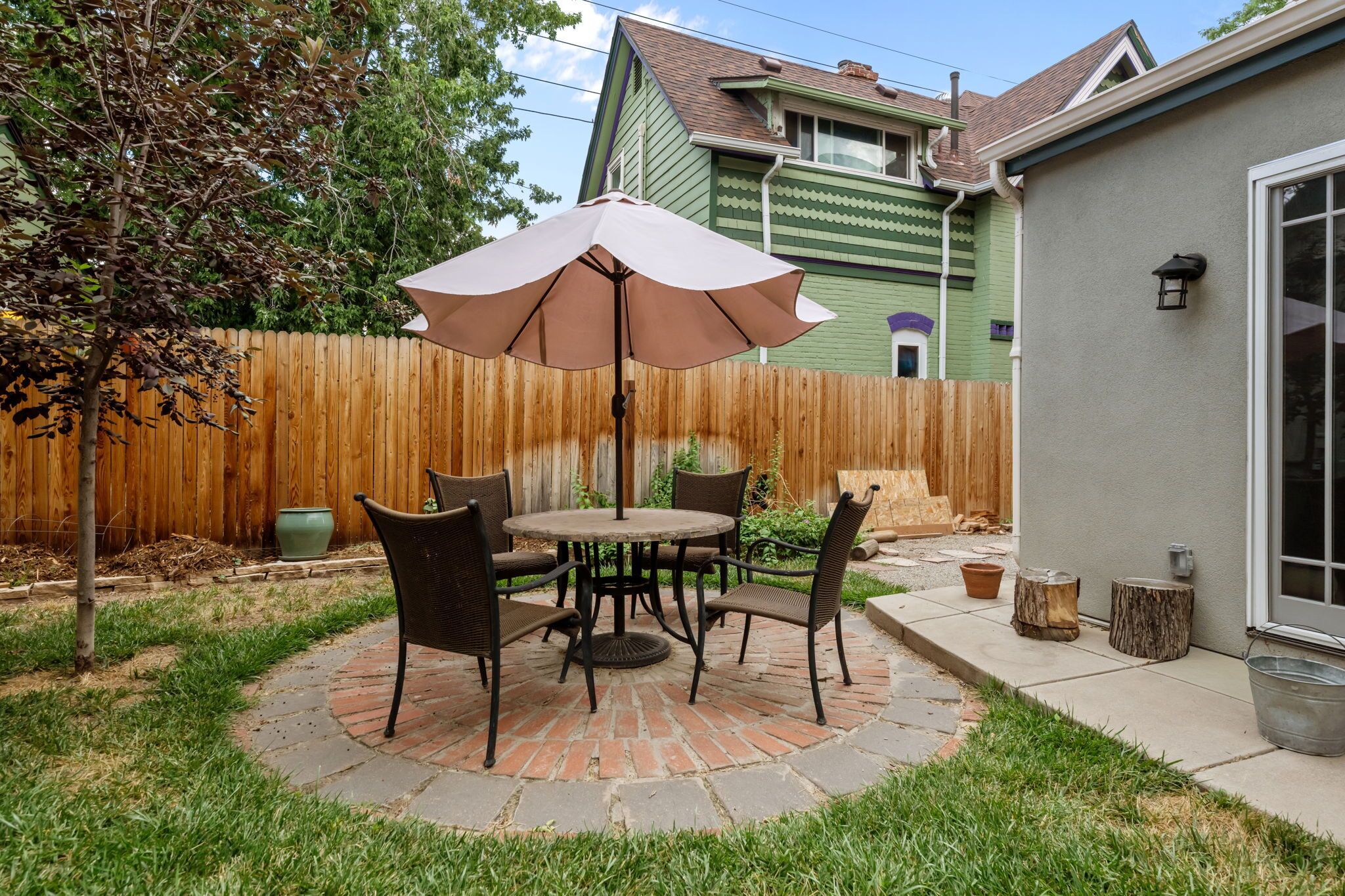A patio with a table and chairs, a wooden fence, and a house in the background.