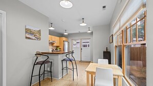 A compact kitchen with a dining area, bar stools, and a view through large windows. - New! Private Carriage House | Walk to Broadway Shops & Restaurants (Denver)