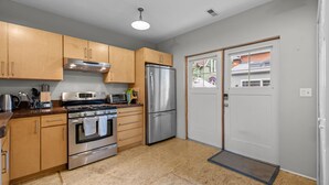 A modern kitchen with stainless steel appliances, wooden cabinets, and a double door. - New! Private Carriage House | Walk to Broadway Shops & Restaurants (Denver)