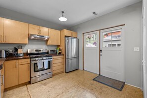 A modern kitchen with stainless steel appliances, wooden cabinets, and a double door. - New! Private Carriage House | Walk to Broadway Shops & Restaurants (Denver)