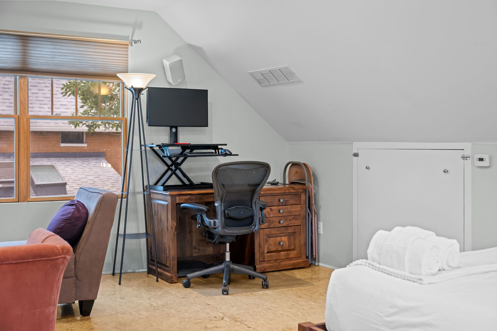 A room with a desk, chair, and a bed.