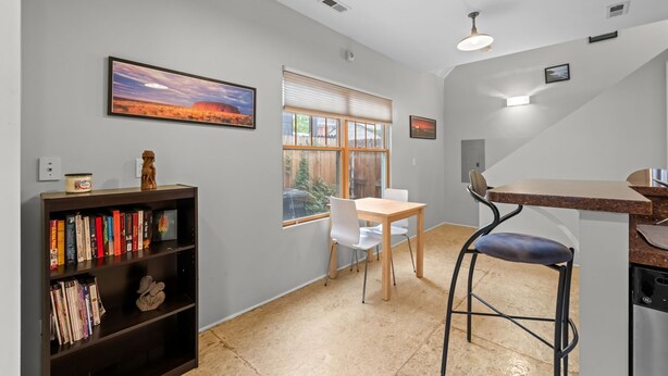 A modern kitchen with a dining area, a bookshelf, and a window with a view of a building. - New! Private Carriage House | Walk to Broadway Shops & Restaurants (Denver)