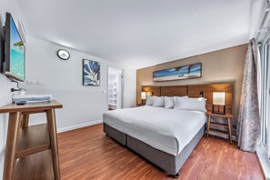 A hotel room with a large bed, bedside tables, a flat-screen TV, artwork on the walls, and a window with curtains. - Whitsunday Blue Penthouse (Airlie Beach)