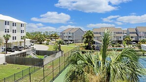 A residential area with multiple apartment buildings, a fenced yard, and a swimming pool. - 🌊Coastal Townhouse | Pool & Tennis Court | Walk2Beach | Barrier Dunes 542 - 55 (Cape San Blas)