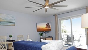 A hotel room with a bed, a desk, a chair, a ceiling fan, a window, and a painting on the wall. - 🌊Coastal Townhouse | Pool & Tennis Court | Walk2Beach | Barrier Dunes 542 - 55 (Cape San Blas)