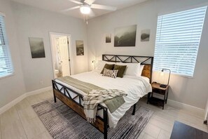 Una camera da letto con un letto, comodini, una ventola a soffitto e opere d'arte alle pareti.