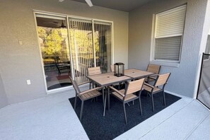 A covered patio with a table and chairs, a sliding glass door, and a window with blinds. - Peaceful & Modern Retreat - Pool & Themed Rooms! (Davenport)