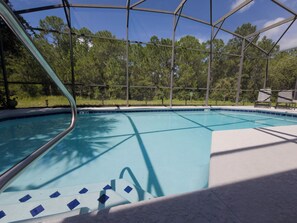 A clear blue pool with a safety fence, surrounded by trees and a clear sky. - Peaceful & Modern Retreat - Pool & Themed Rooms! (Davenport)
