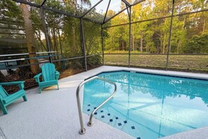 An outdoor swimming pool with a glass enclosure, surrounded by trees and equipped with a metal ladder. - Peaceful & Modern Retreat - Pool & Themed Rooms! (Davenport)