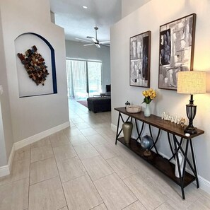 A hallway with a console table, artwork, and a decorative wall piece. - Peaceful & Modern Retreat - Pool & Themed Rooms! (Davenport)