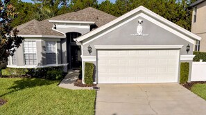 Una casa residencial con garaje, un pequeño garaje adosado y un césped bien cuidado.