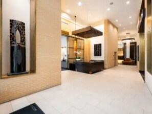 A modern hotel lobby with a reception desk, a seating area, and a large artwork on the wall. - Furnished 1-bedroom apartment in Arlington with garage onsite parking included (Arlington)