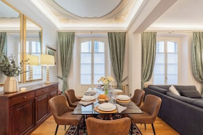 A dining area with a table set for four, surrounded by chairs, a sofa, and a cabinet. - Churchkey by Rent All Como (Como)