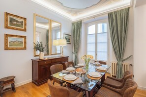 Comedor con una mesa de vidrio dispuesta para cuatro personas, rodeado de sillas acolchadas.