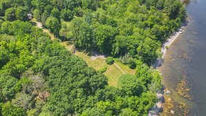 Une vue aérienne d’une zone boisée, avec un sentier bien défini menant à un plan d’eau.