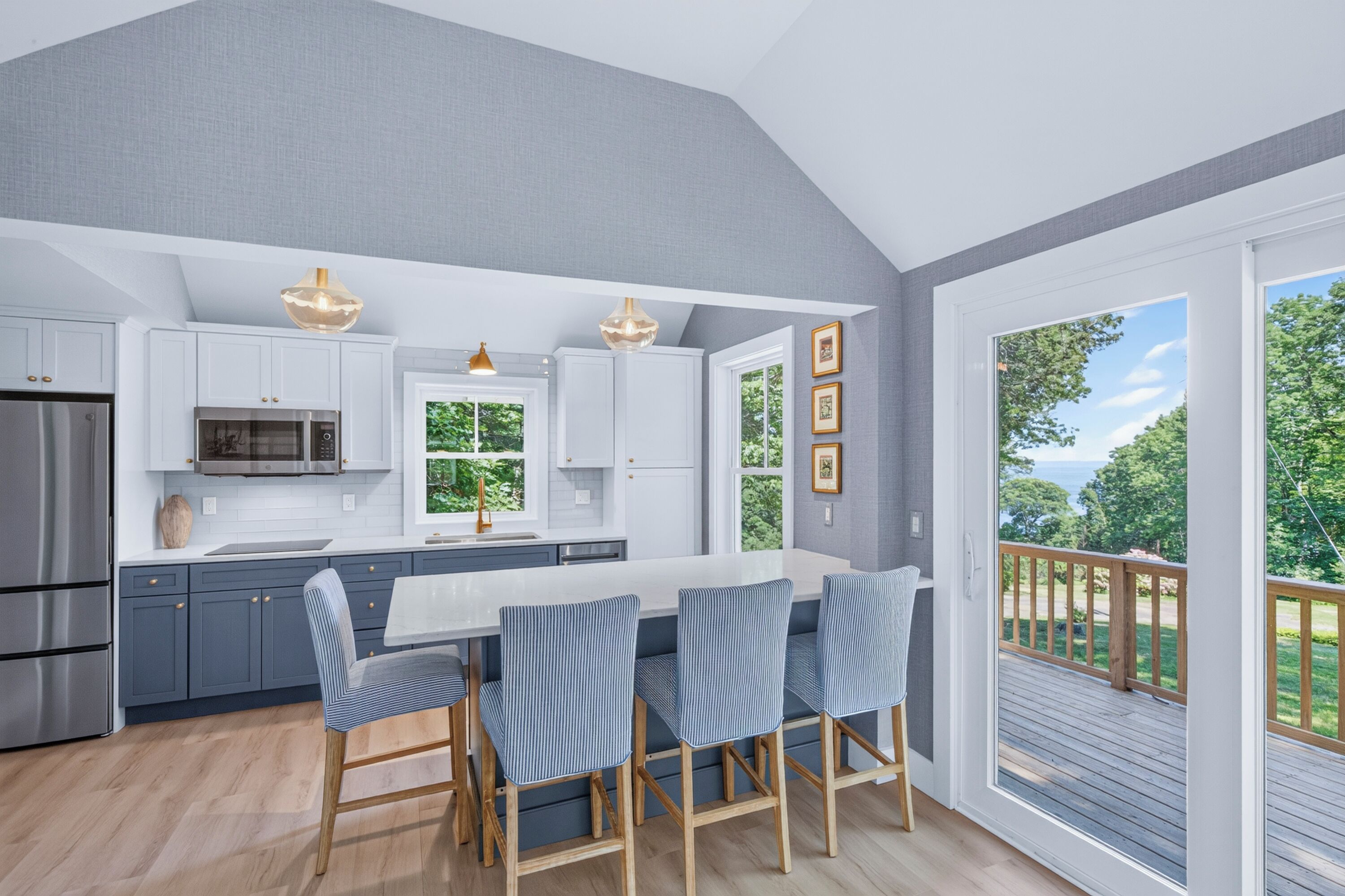 A modern kitchen with a central island, stainless steel appliances, and a view of the outdoors.
