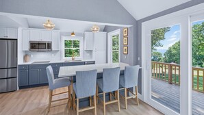 Une cuisine moderne dotée d’un îlot central, d’appareils électroménagers en acier inoxydable et offrant une vue sur l’extérieur.