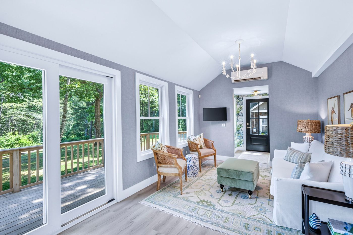 A spacious room with large windows, a comfortable seating area, a flat-screen TV, and a decorative lamp.
