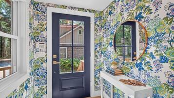 A room with a dark door, a white console table with a mirror, and floral wallpaper.