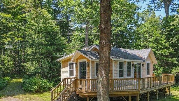 Une cabane dotée d’une terrasse, entourée d’arbres.