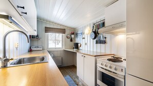 Une cuisine dotée d’un plan de travail en bois, d’un évier en acier inoxydable, d’une cuisinière et d’une fenêtre offrant une belle vue.