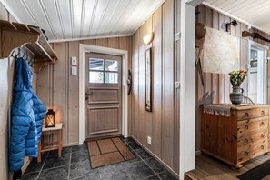 Un interior de madera con una puerta, un perchero, un banco, un aparador y un mapa en la pared.
