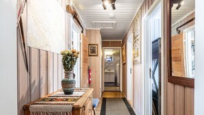 Un couloir aux murs en bois, avec un banc en bois, un tapis et une porte donnant sur une pièce.