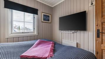A bedroom with a bed, a window with a view, a mounted TV, and a wooden door.