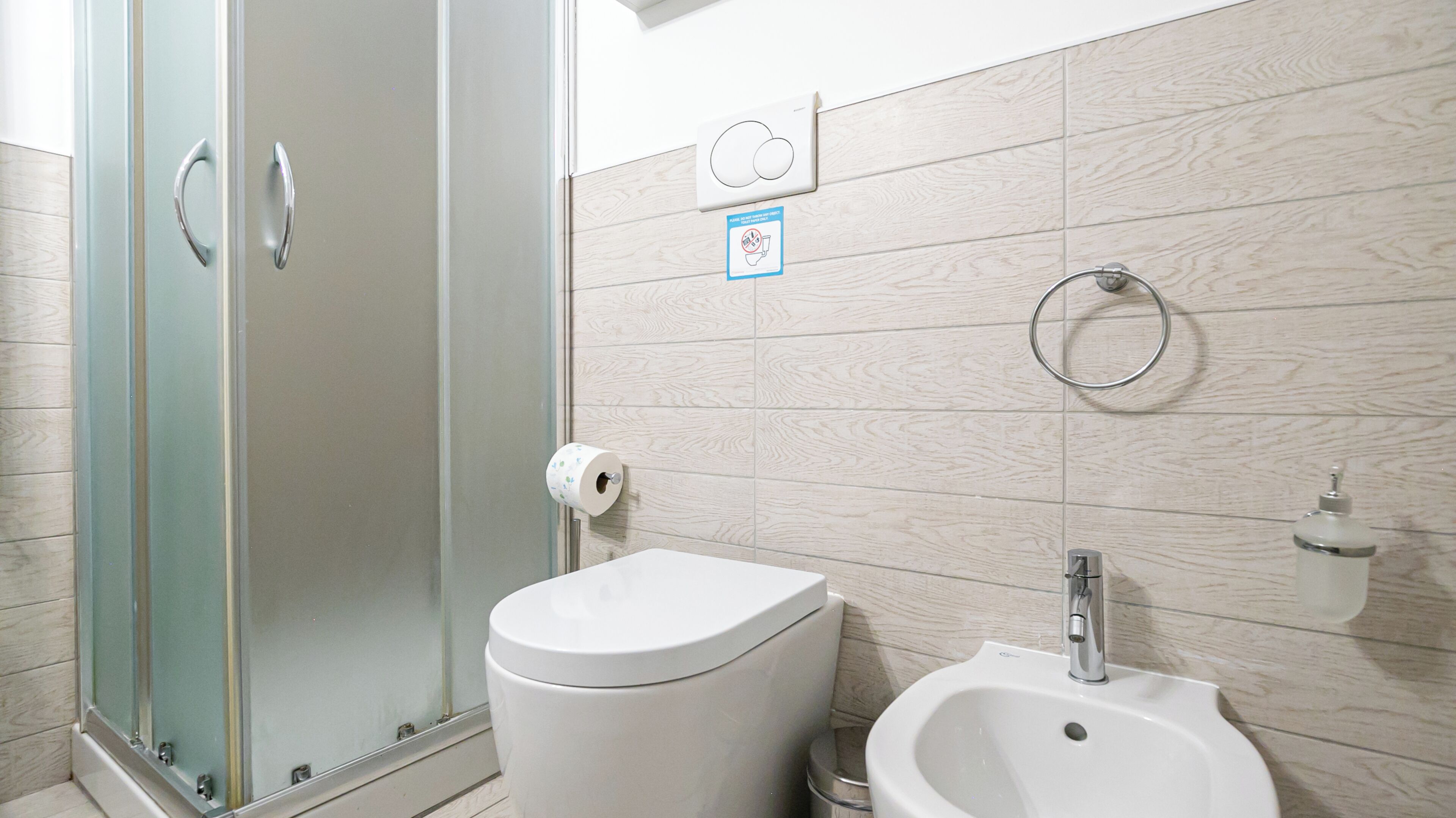 A bathroom with a toilet, bidet, and glass shower enclosure.