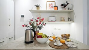 A kitchen with a coffee maker, a bowl of fruit, a basket of bread, and a breakfast setting. - Italianway Comfort - Bligny 19 E (Milan)