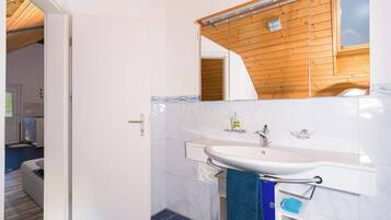 A bathroom with a white sink, a mirror, and a wooden ceiling.