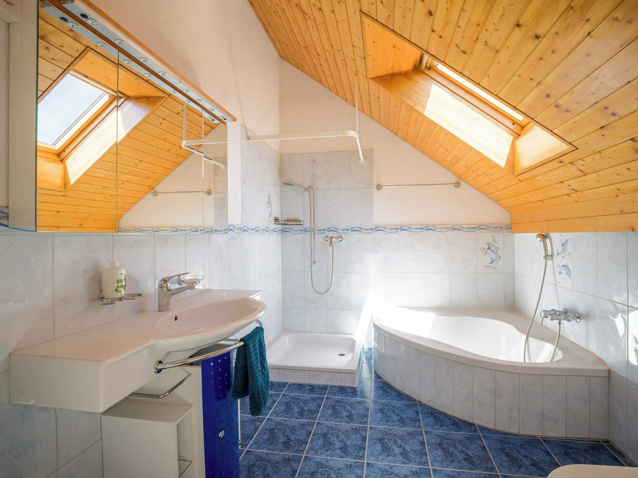 Une salle de bain moderne dotée d’une lucarne, d’une baignoire, d’une douche et d’un lavabo.