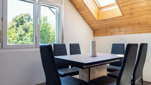A room with a sloped ceiling, a skylight, a table with chairs, and a window with a view of trees. - Central Apartment near Bern, Parking & Balcony (Ried bei Kerzers)