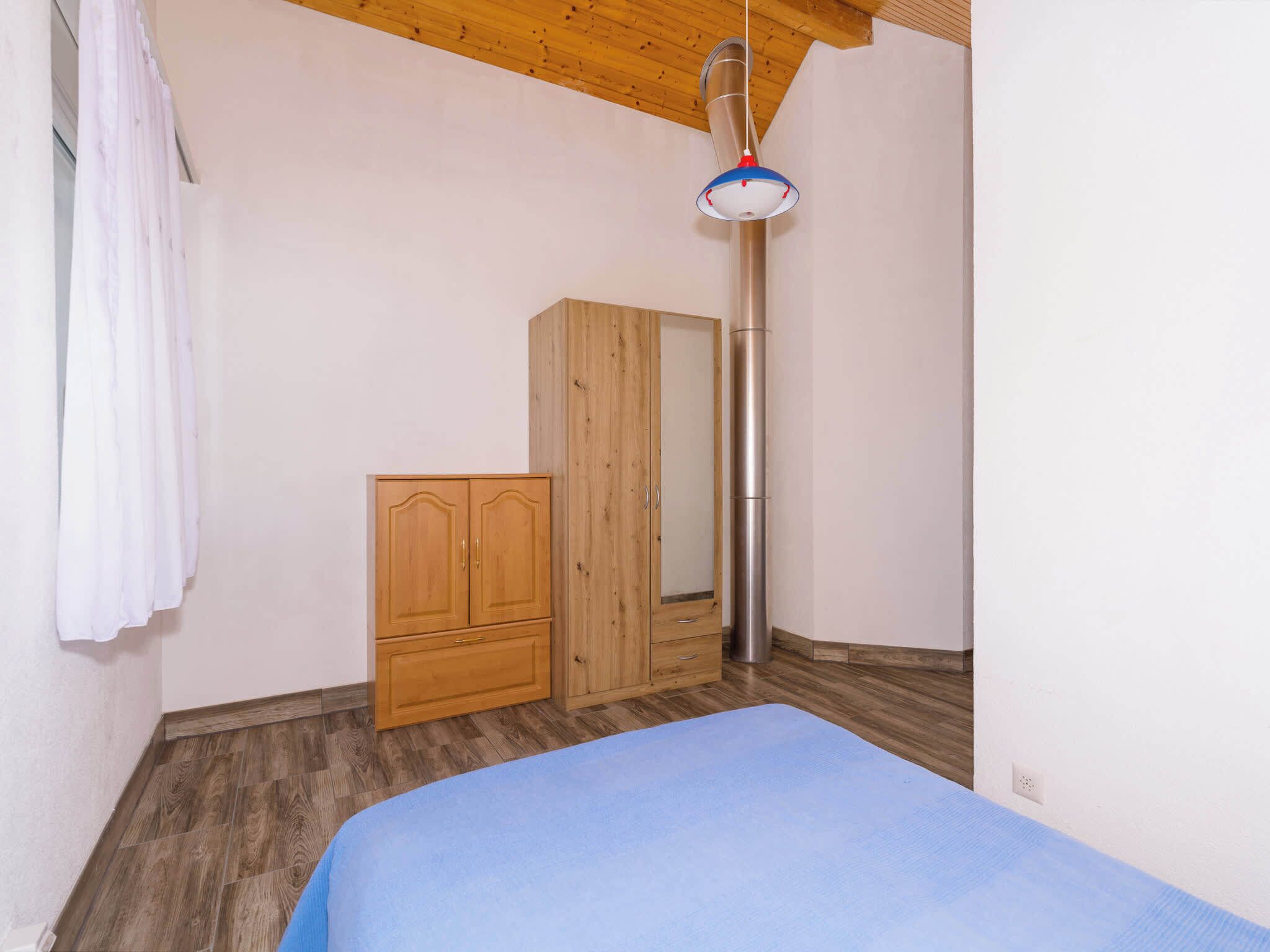 A bedroom with a bed, wooden wardrobe, and a tall, narrow light fixture.
