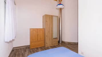 A bedroom with a bed, wooden wardrobe, and a tall, narrow light fixture.