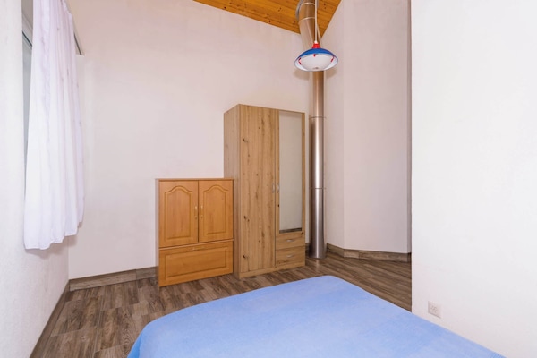 Bright bedroom with double bed, wardrobe, and wooden ceiling details.