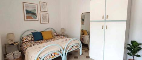 A bedroom with a bed, bedside tables, a wardrobe, and a potted plant.
