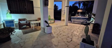 An outdoor patio area with stone flooring, seating arrangements, and a table.