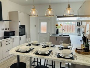 A modern kitchen with a marble countertop, black and white cabinetry, and pendant lighting.